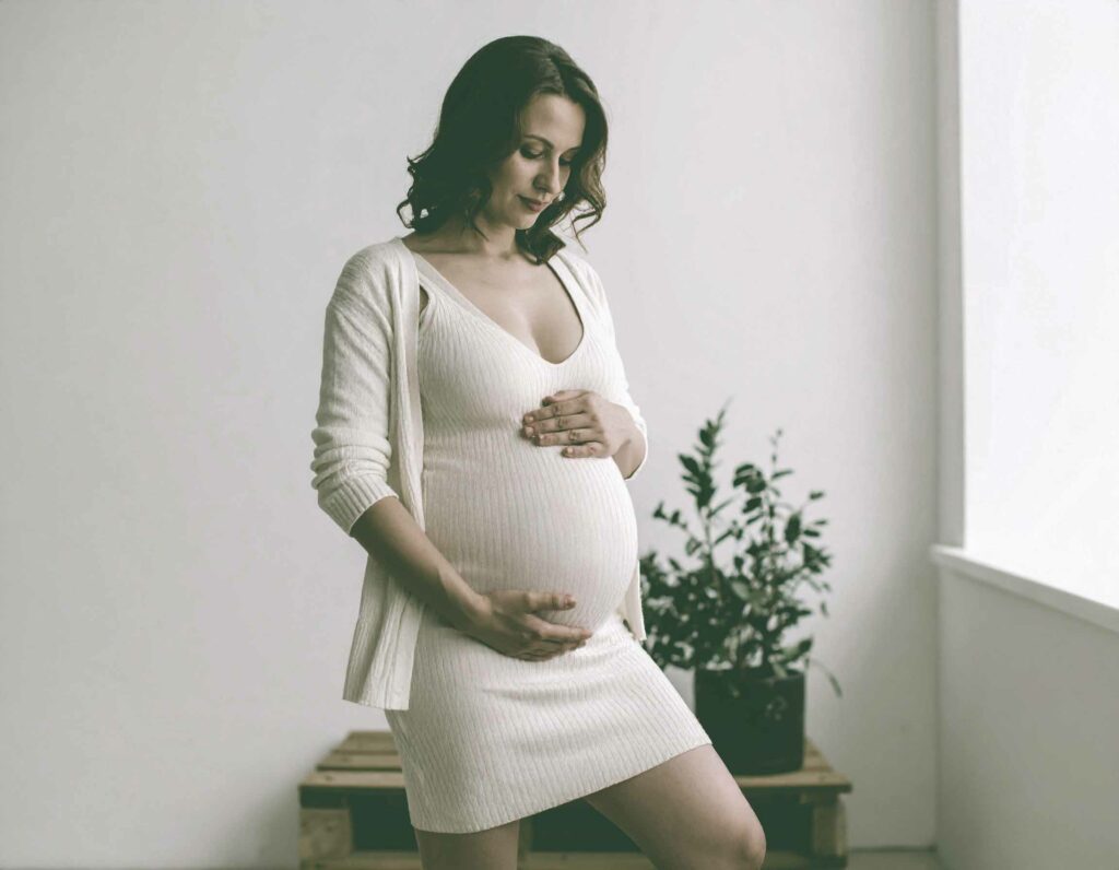 Expecting mother holding her belly in a simple contemporary room